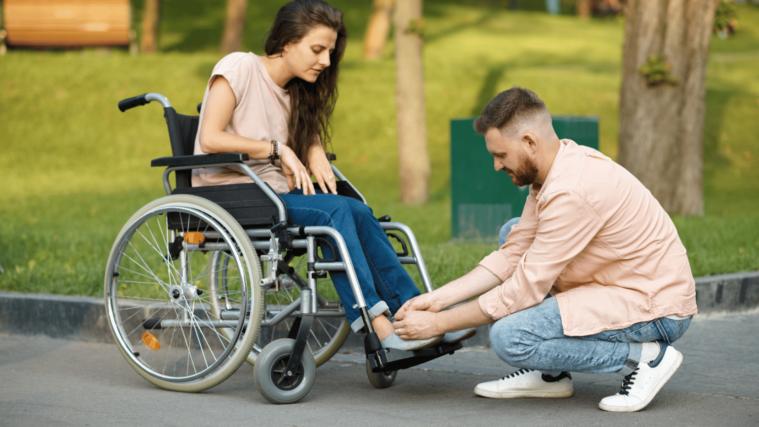 man-helps-woman-in-wheelchair-with-shoe