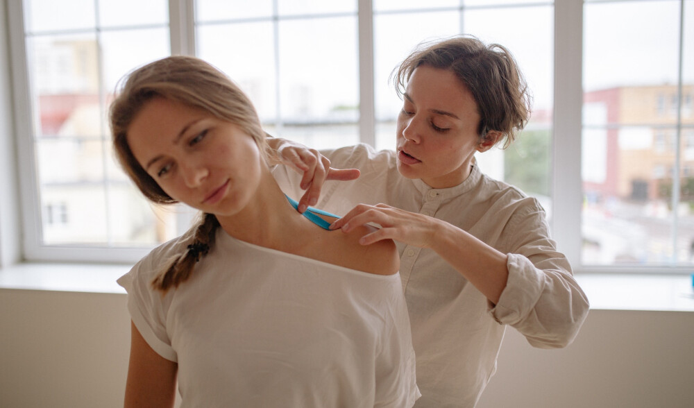 A woman applies bandage to a woman's neck.