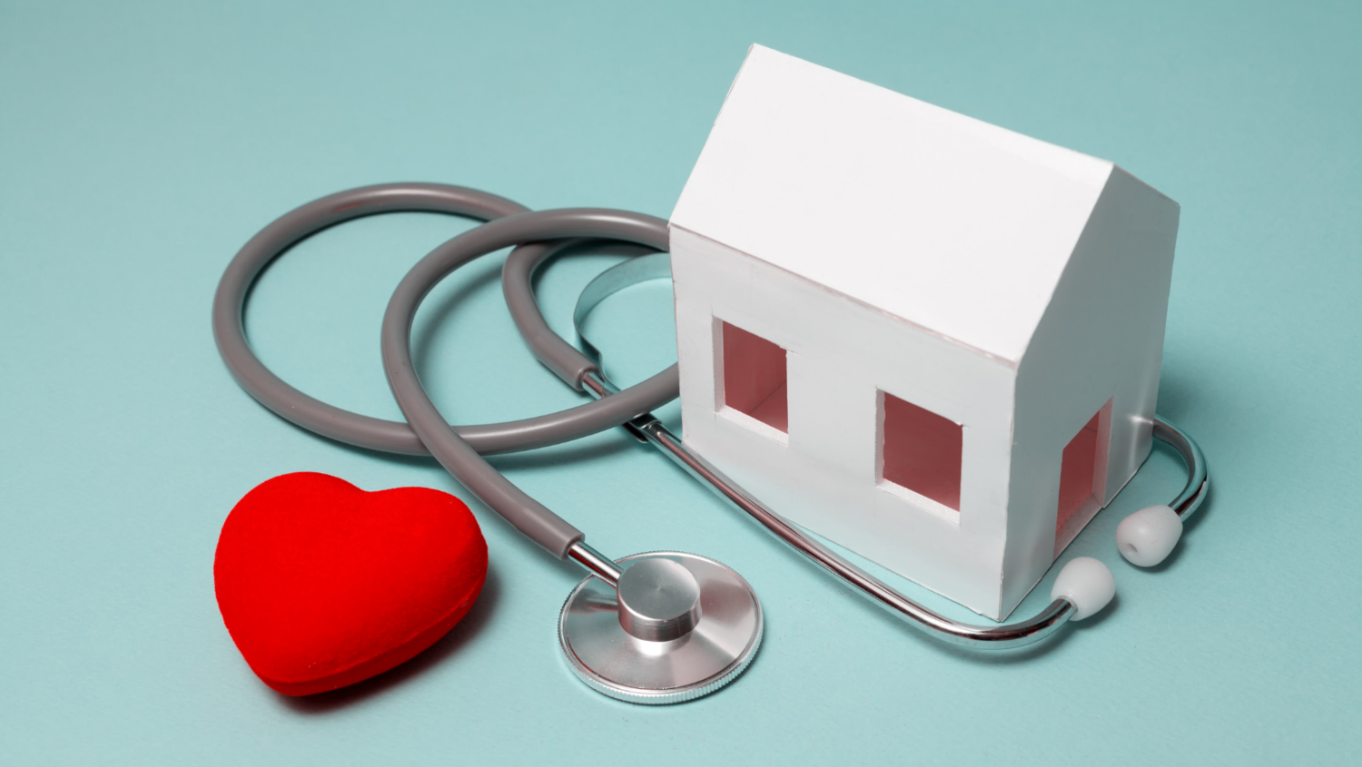 miniature-house-stethoscope-heart-green-background