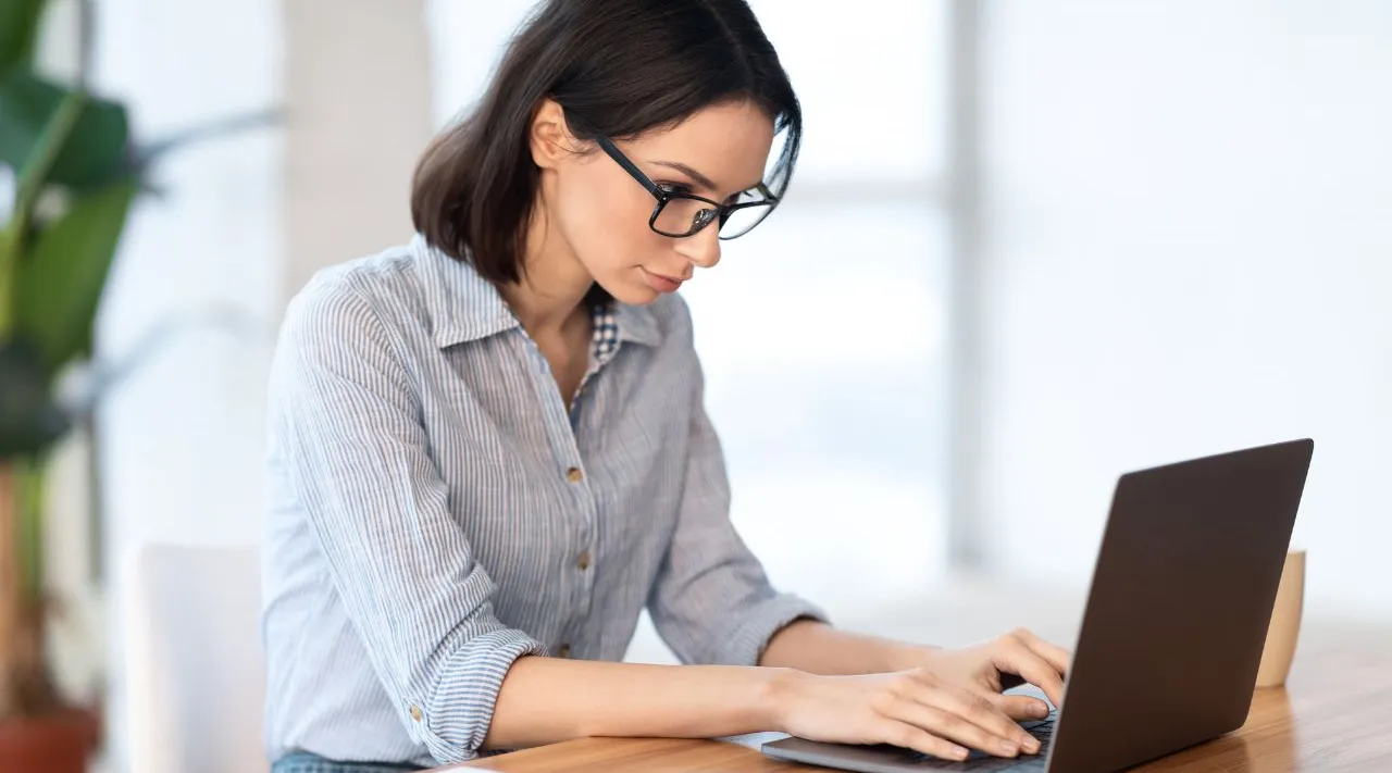 Professional woman working on laptop at modern office, ShiftCare.