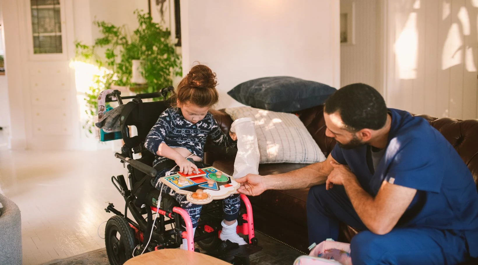 Support worker assisting a young girl in a wheelchair with activities using ShiftCare software.