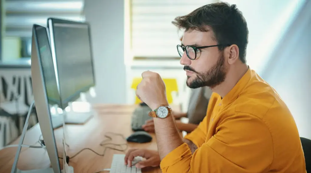 Focused professional analyzing data on a desktop computer to optimize ShiftCare’s software system.