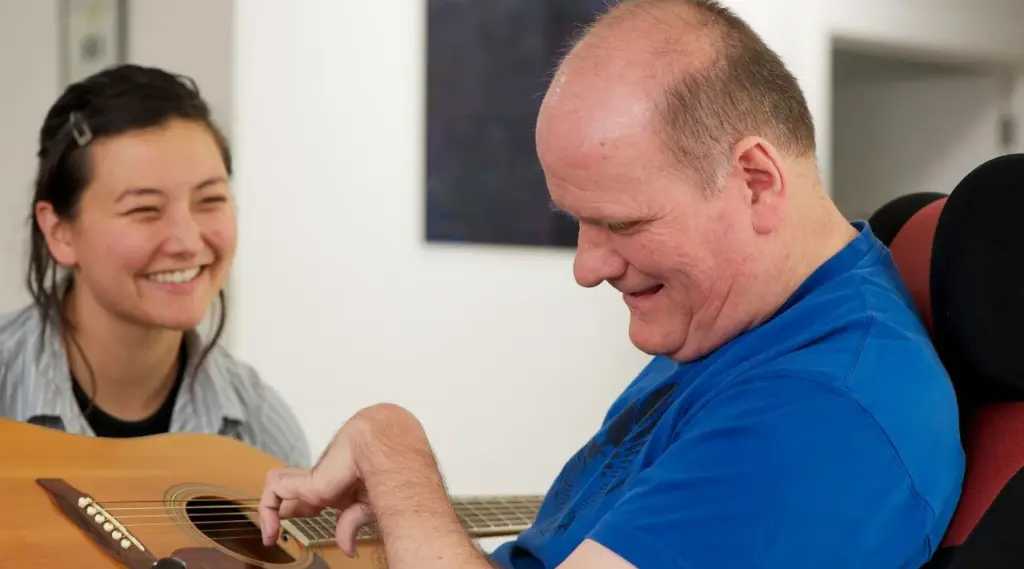 Disability transport support with carer helping wheelchair client, ShiftCare.