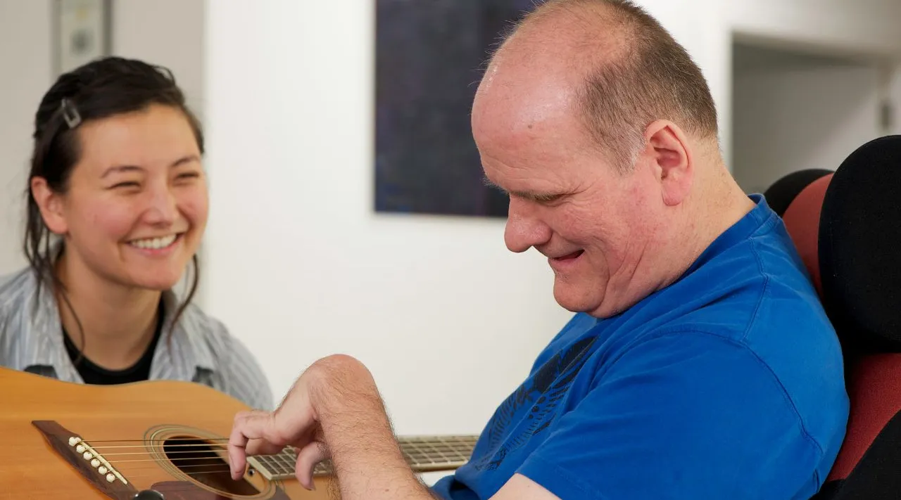 Disability transport support with carer helping wheelchair client, ShiftCare.