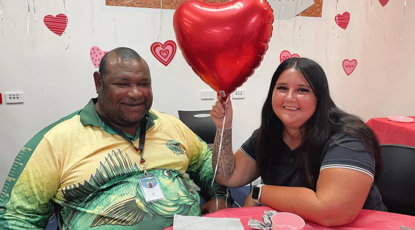 Support worker and participant share joyful moment at community Valentine’s Day event.