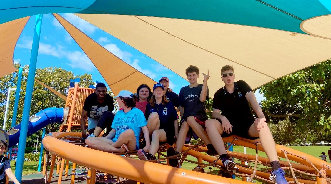 Happy group at shaded playground enjoying community inclusion activity with AbilitiesNQ team.