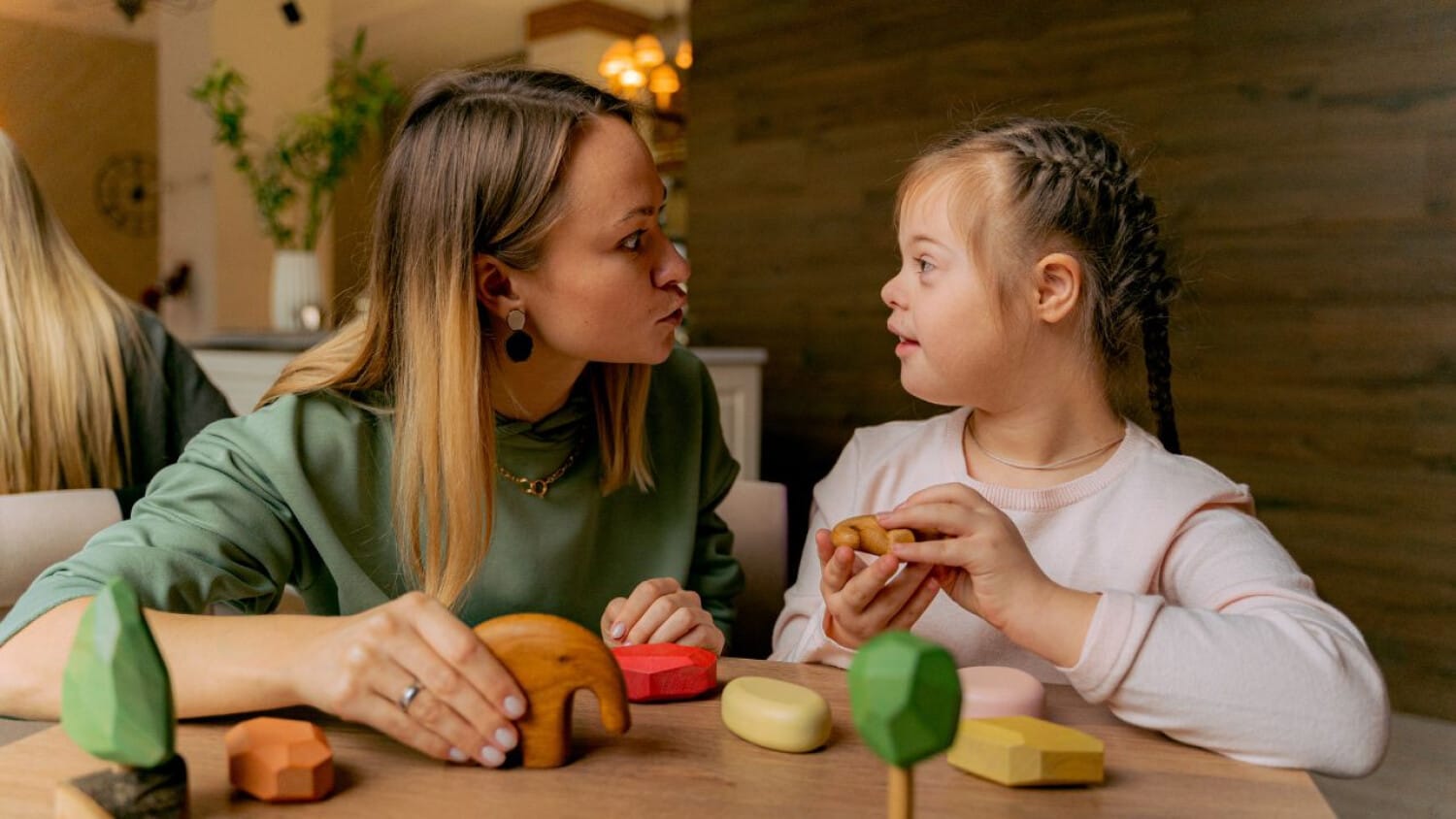 Caregiver supporting a child with Down syndrome during a learning activity, ShiftCare.