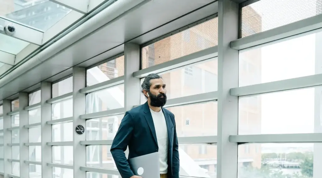 Confident professional walking through modern office with laptop, representing ShiftCare.