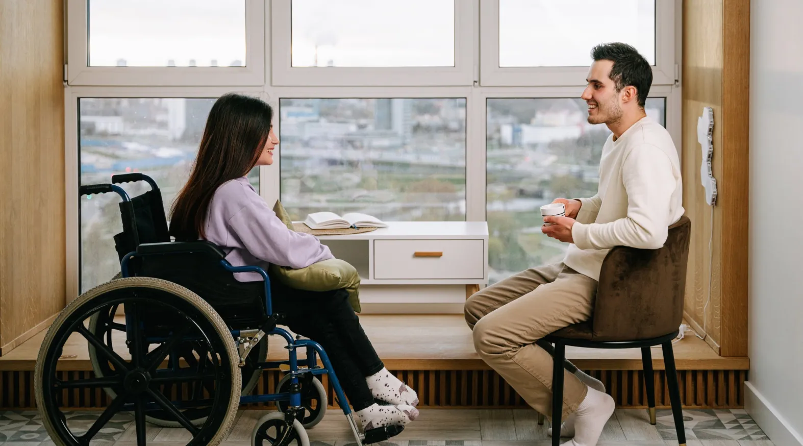 NDIS participant in wheelchair consulting with occupational therapist — supported by ShiftCare.