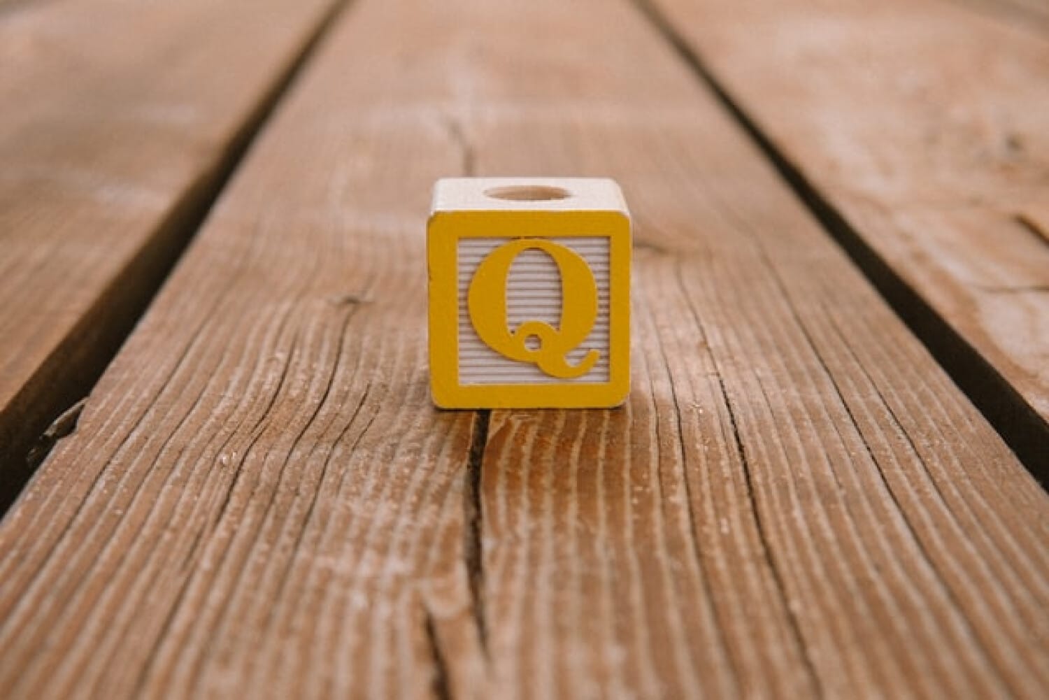 Yellow Q block on wooden floor symbolizing quality in care