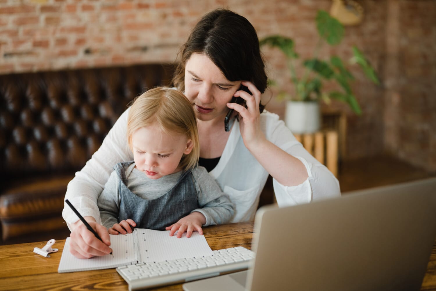 Care provider working from home with child, showcasing flexible remote work using ShiftCare.