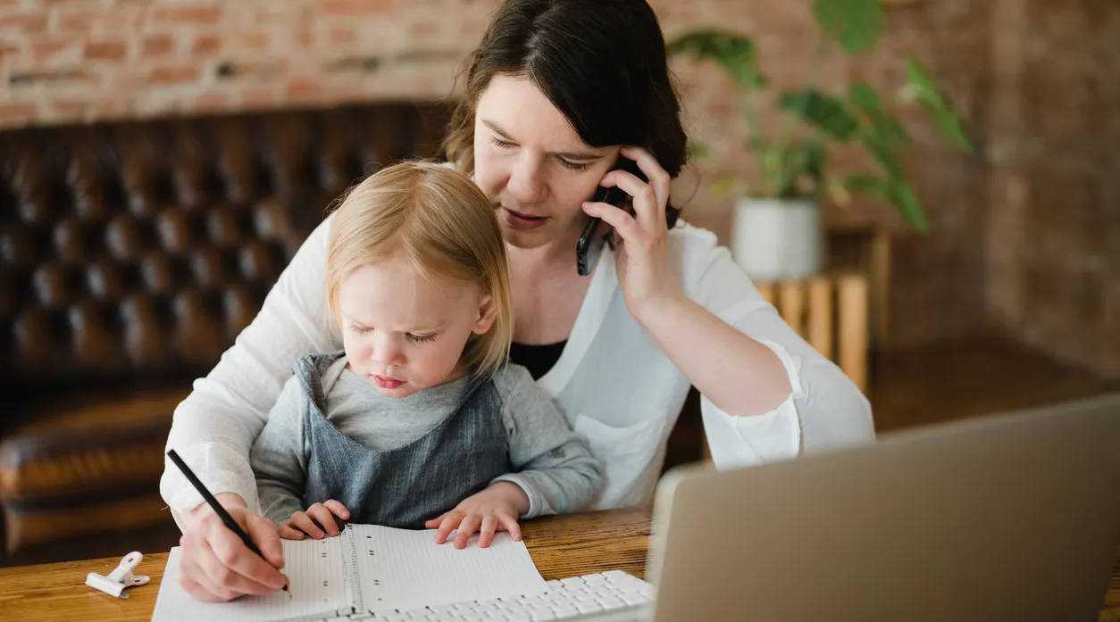 Care provider working from home with child, showcasing flexible remote work using ShiftCare.