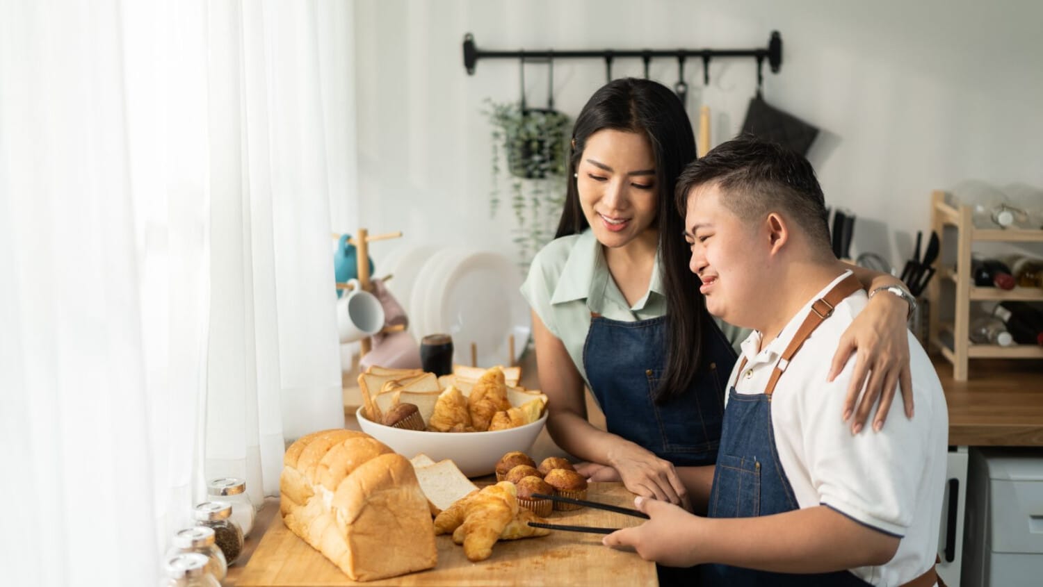NDIS participant preparing bread and pastries with assistance, promoting independent living skills.