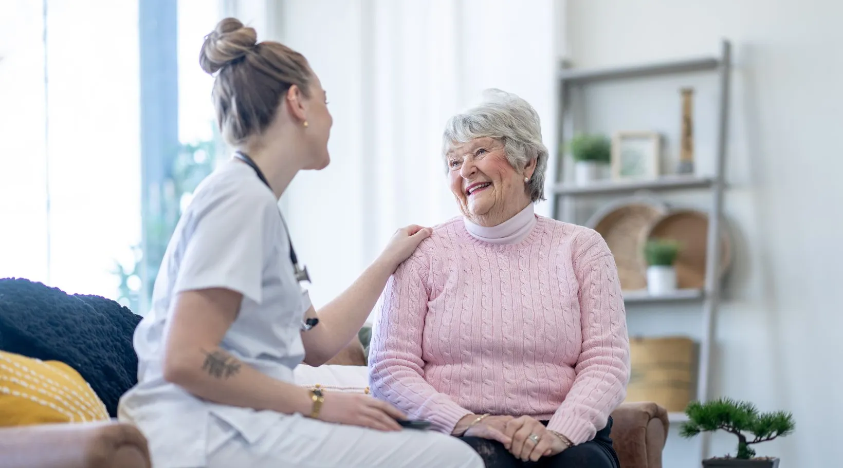 Nurse talking with elderly woman at home showing care and companionship, ShiftCare.