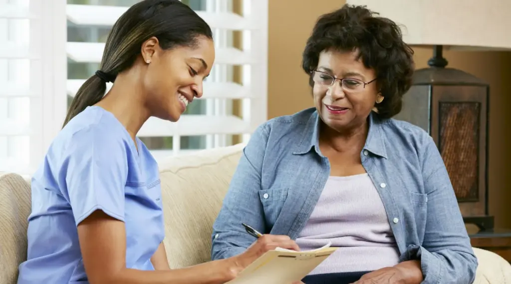 Care worker assisting elderly woman with paperwork at home, ShiftCare.