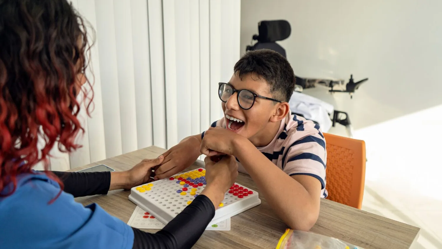 Disability support worker engaging happy child in home care activity, ShiftCare.