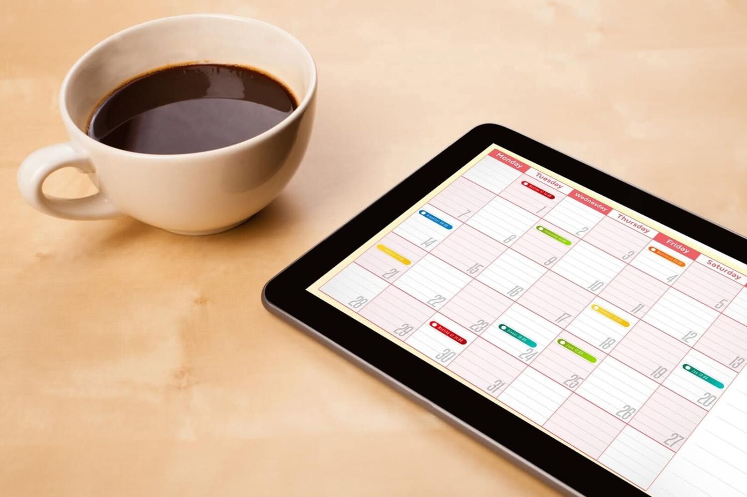 Coffee cup beside tablet showing digital schedule for home care team using ShiftCare.