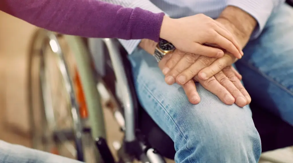 NDIS support worker reassuring a client in a wheelchair, representing compassionate care by ShiftCare.