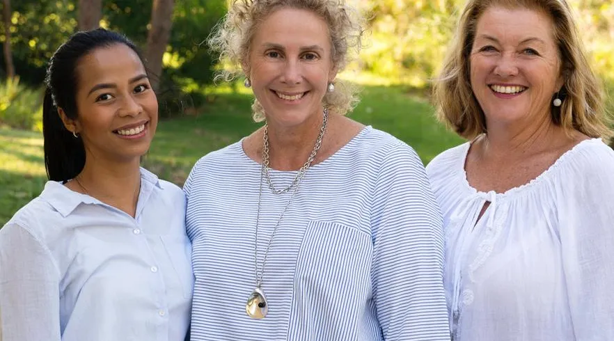 Three smiling aged care providers outdoors, representing teamwork and compassionate support with ShiftCare.