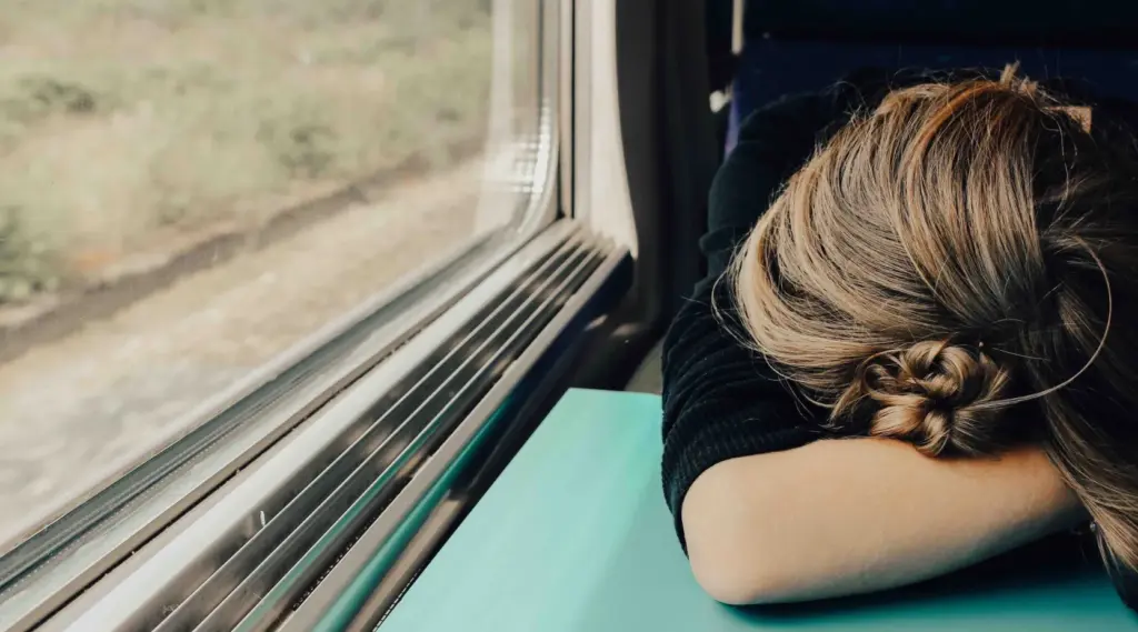 Exhausted employee resting on train table, symbolising caregiver burnout and fatigue.