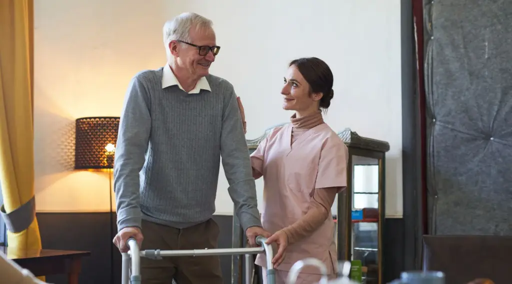 Caregiver assisting elderly man with walker during home care visit, ShiftCare.
