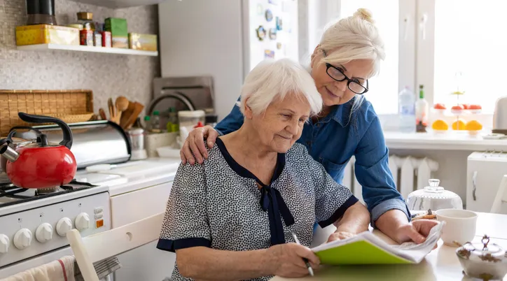 Support worker assisting elderly woman with home care planning using ShiftCare software.