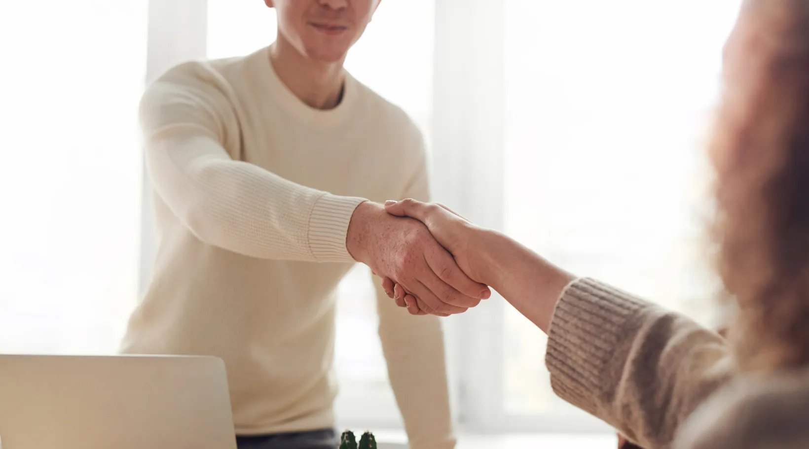 Two professionals shaking hands after a successful NDIS partnership meeting with ShiftCare.