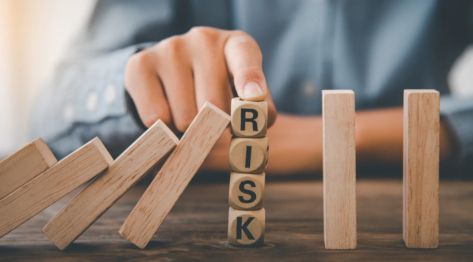 Wooden blocks spelling risk stopping domino chain symbolizing client risk management in home care.