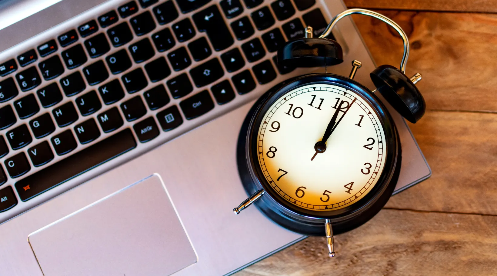 Clock on laptop keyboard representing efficient scheduling and time tracking with ShiftCare software.