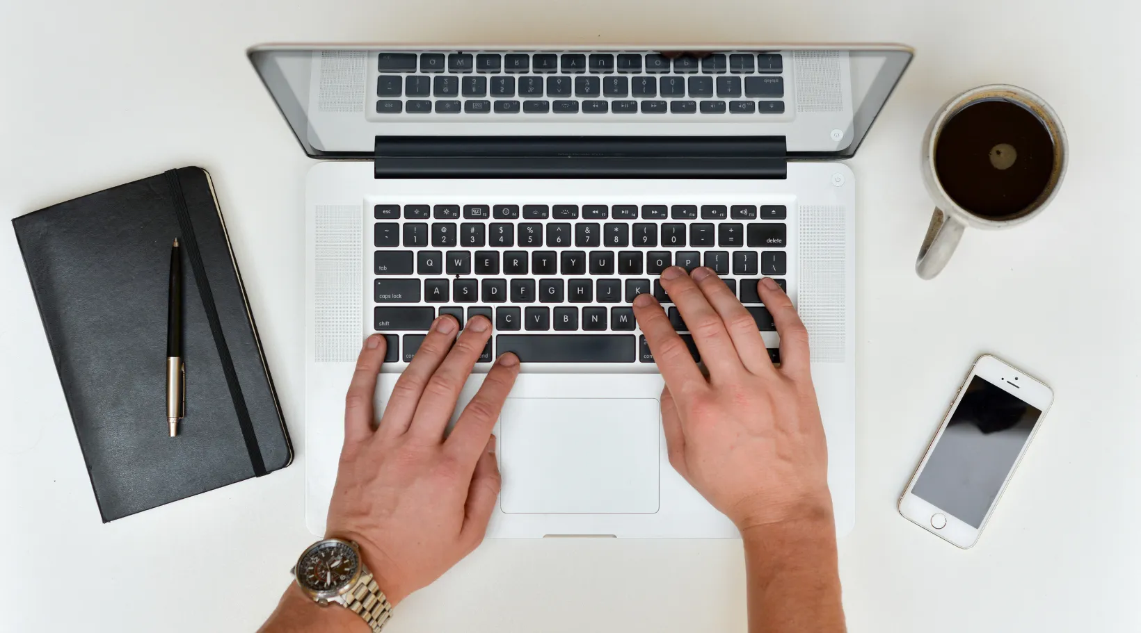 ShiftCare user managing care operations on a laptop with notes, coffee, and phone nearby.