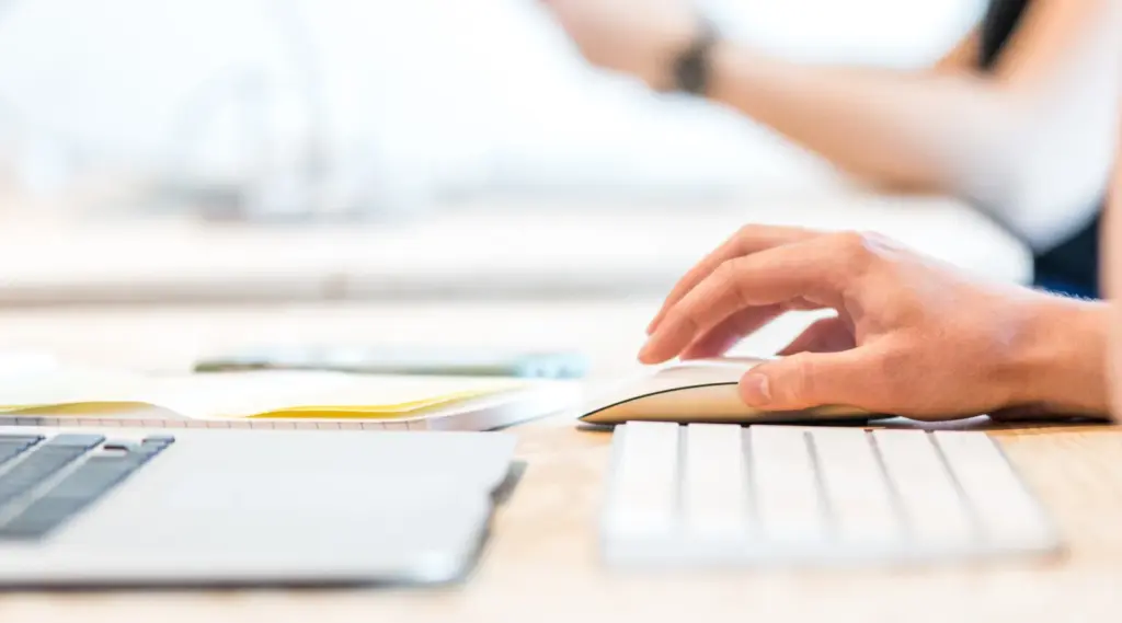 Close-up of a person using a laptop and mouse, representing ShiftCare’s digital tools for care management.