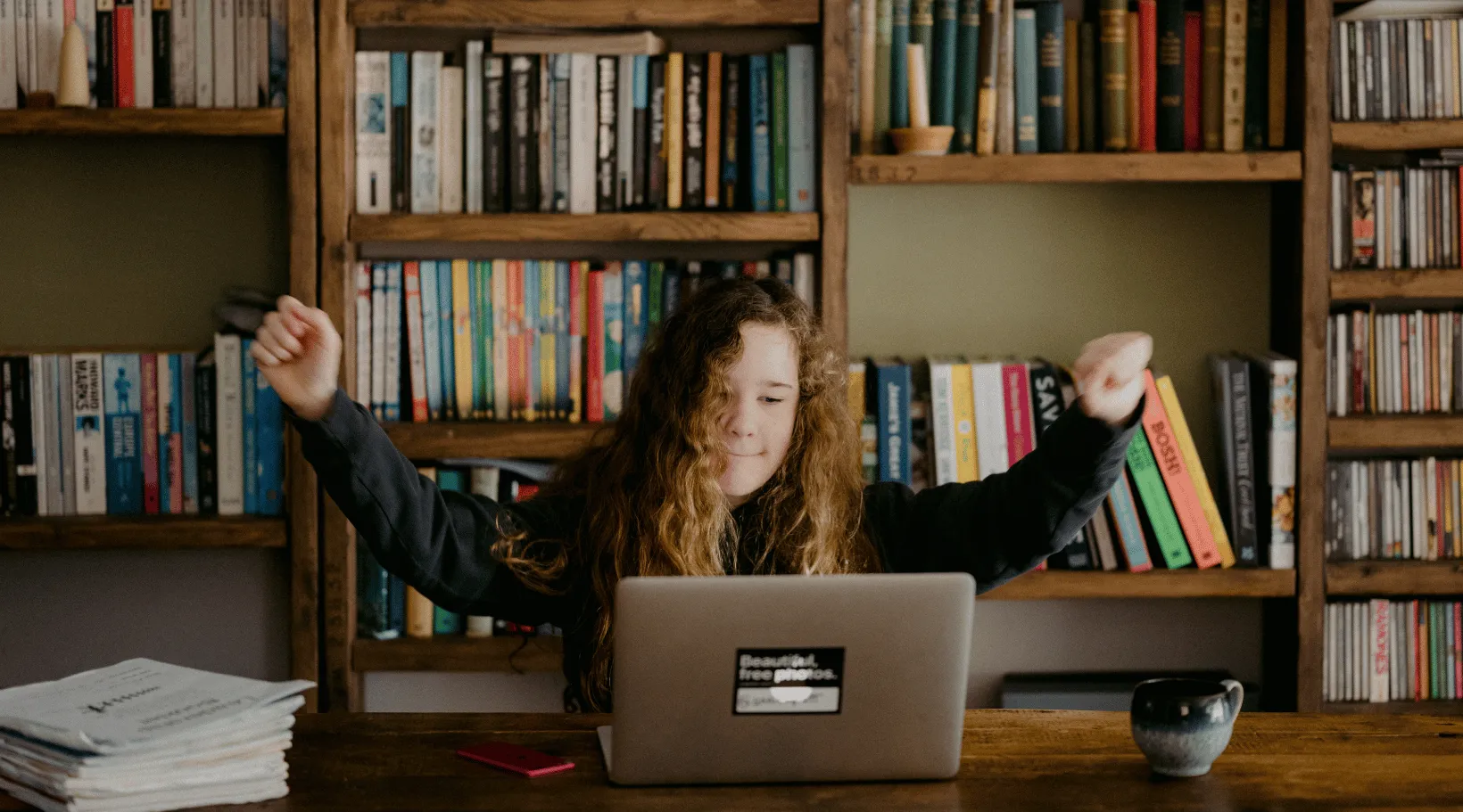 Woman working on laptop with coffee, reading ShiftCare’s free ebook on growing NDIS business.