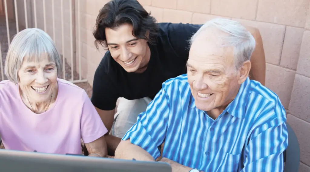 Caregiver assisting older adults with digital tools through ShiftCare home care software.