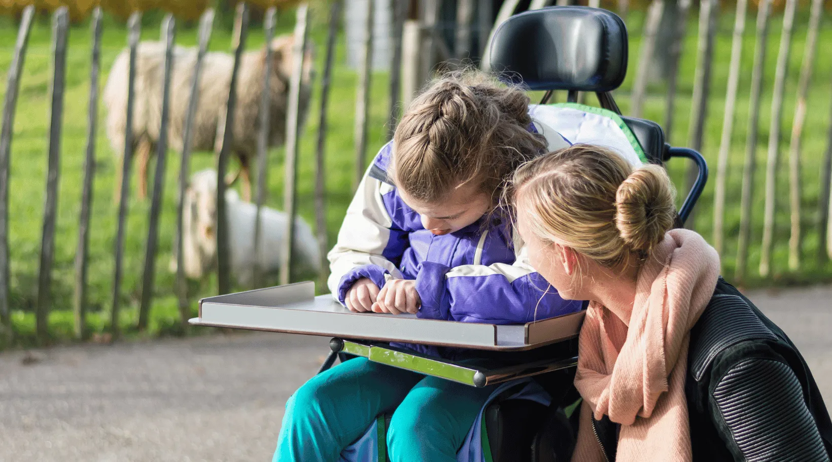 ShiftCare caregiver supporting girl with disability outdoors.