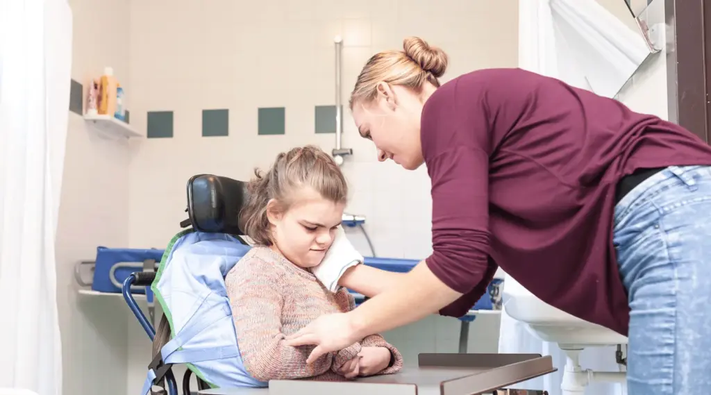 Support worker assisting a child with disability using ShiftCare to manage personalized care tasks.