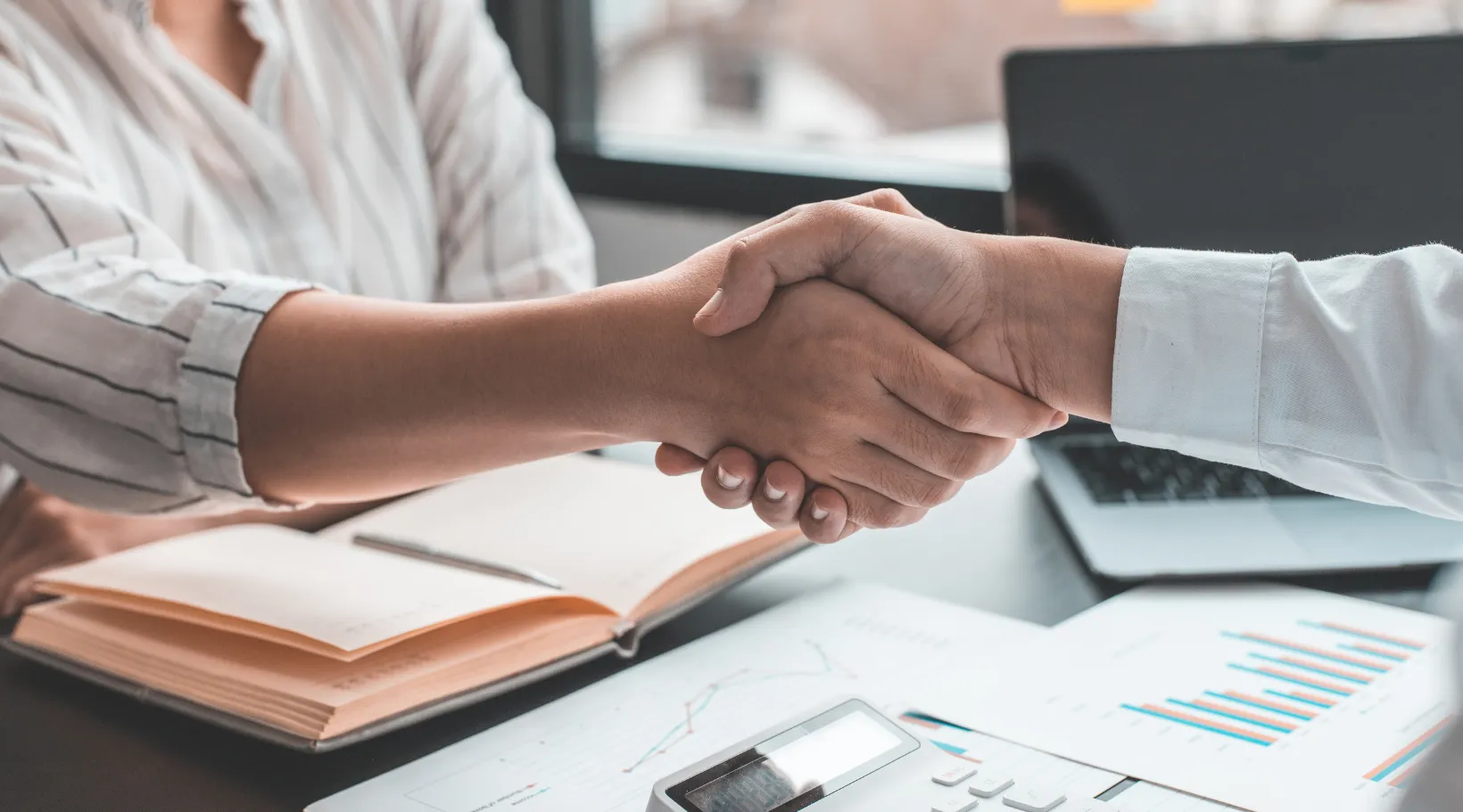 Business partners shaking hands after a successful NDIS collaboration using ShiftCare software.