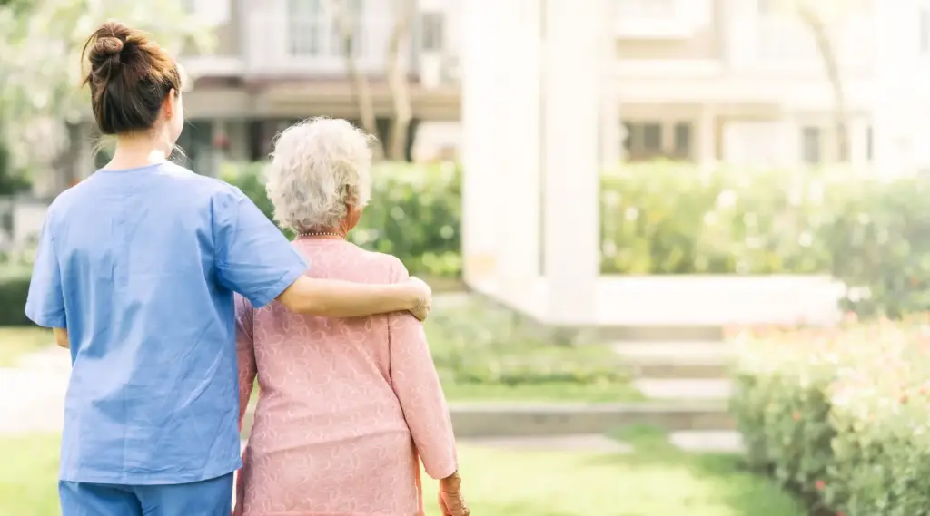 Caregiver walking with elderly client outdoors providing companionship and mobility support.