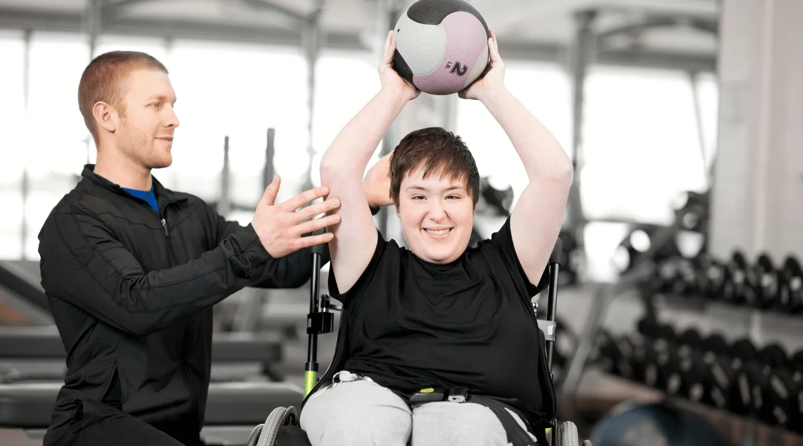 ShiftCare support worker assisting wheelchair user in inclusive fitness session.
