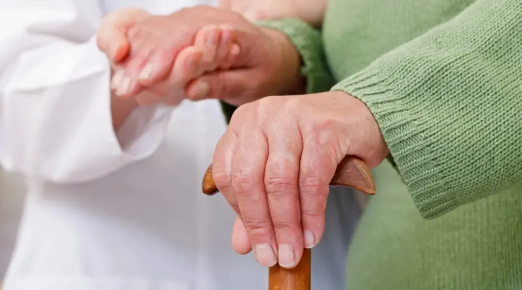 Home caregiver supporting elderly client with walking cane, representing care services coordinated in ShiftCare.