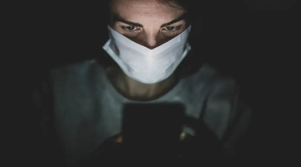 Healthcare safety awareness with masked person using phone, ShiftCare.