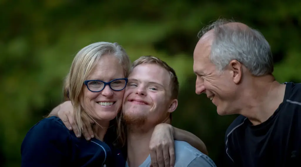 Happy family supporting young man with disability, reflecting ShiftCare’s inclusive values.