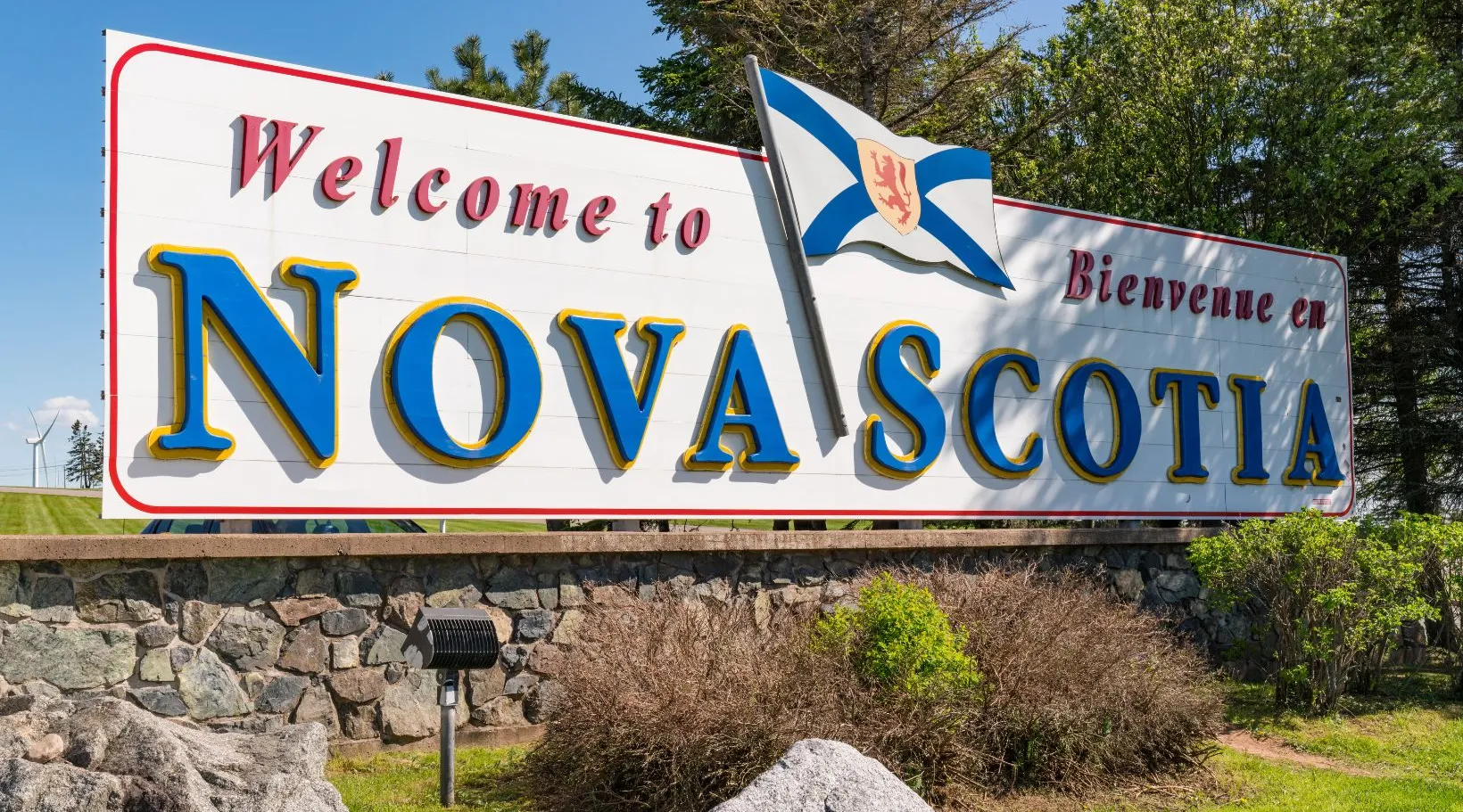 Welcome to Nova Scotia bilingual sign with provincial flag at the Canadian border entrance.