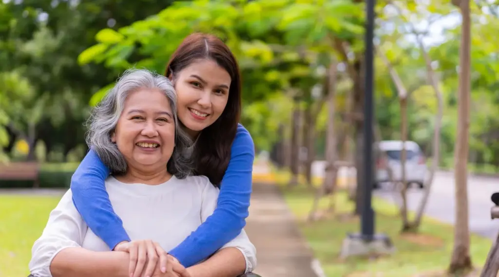 Happy mother and daughter walking together in park, supported by ShiftCare.