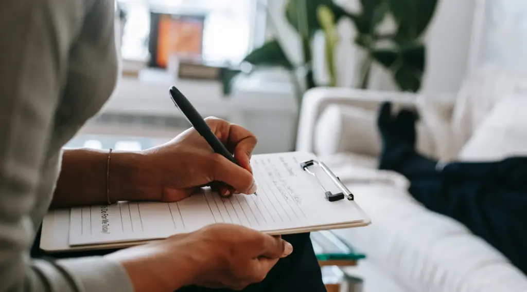 ShiftCare care worker writing notes during home client consultation.
