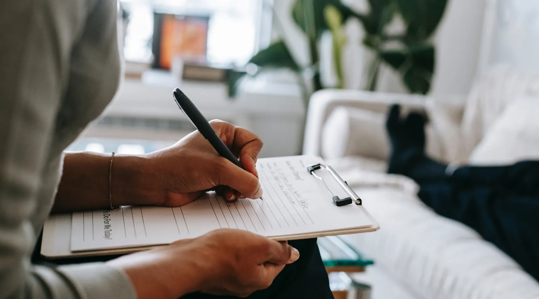 ShiftCare care worker writing notes during home client consultation.