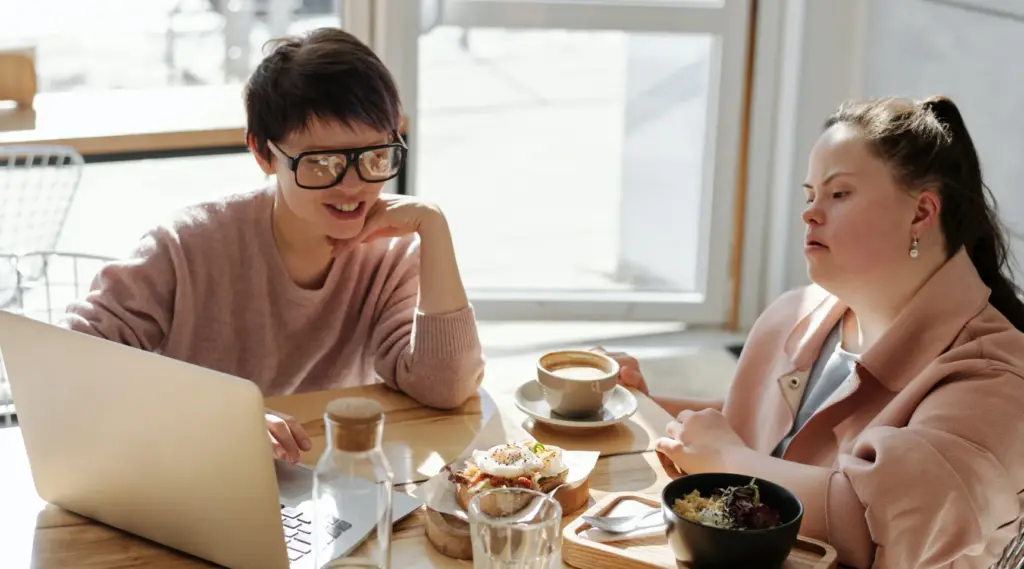 Two women sharing coffee and conversation in care setting, ShiftCare.