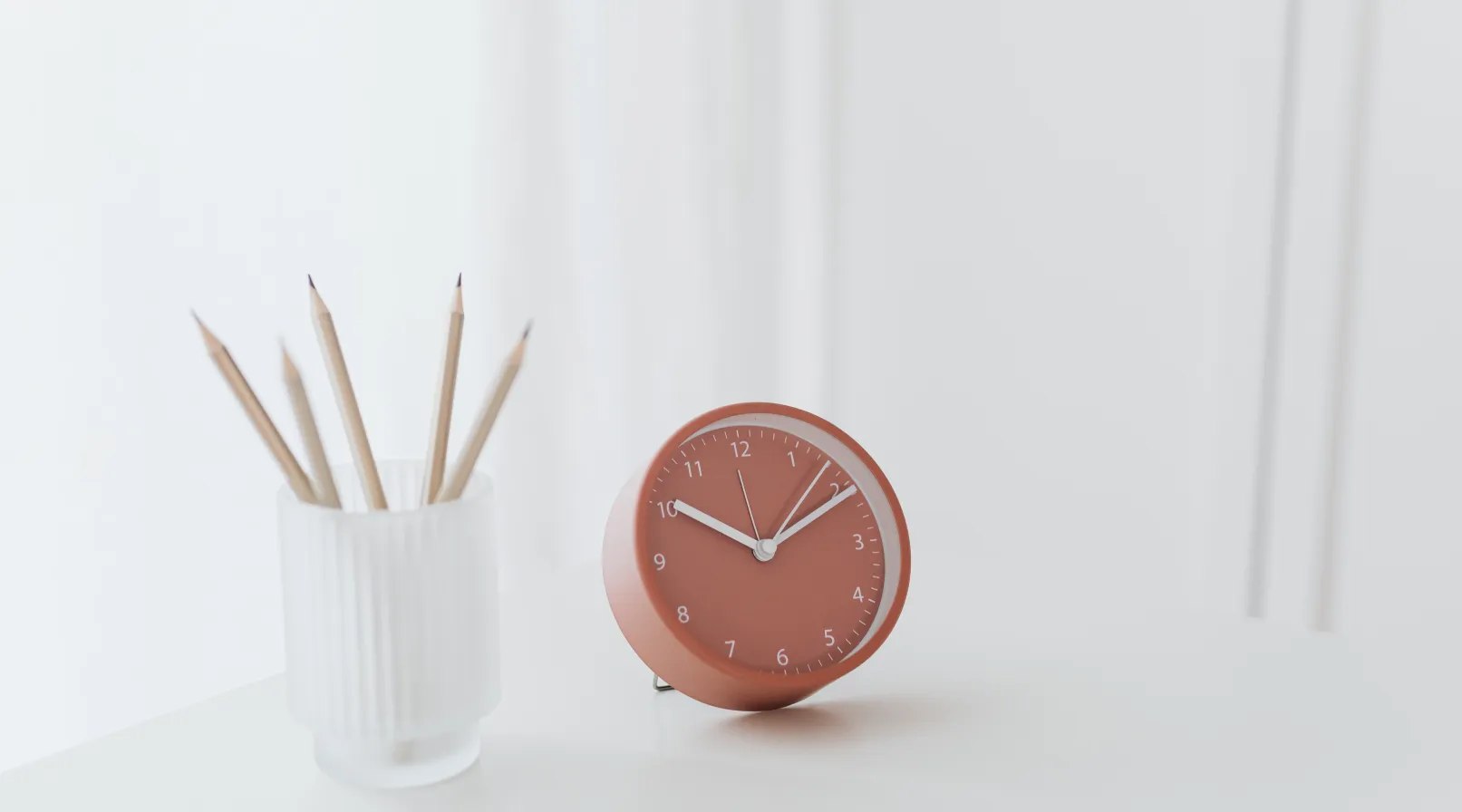 Minimal desk setup with pencils in a cup and a terracotta clock symbolizing ShiftCare time tracking.