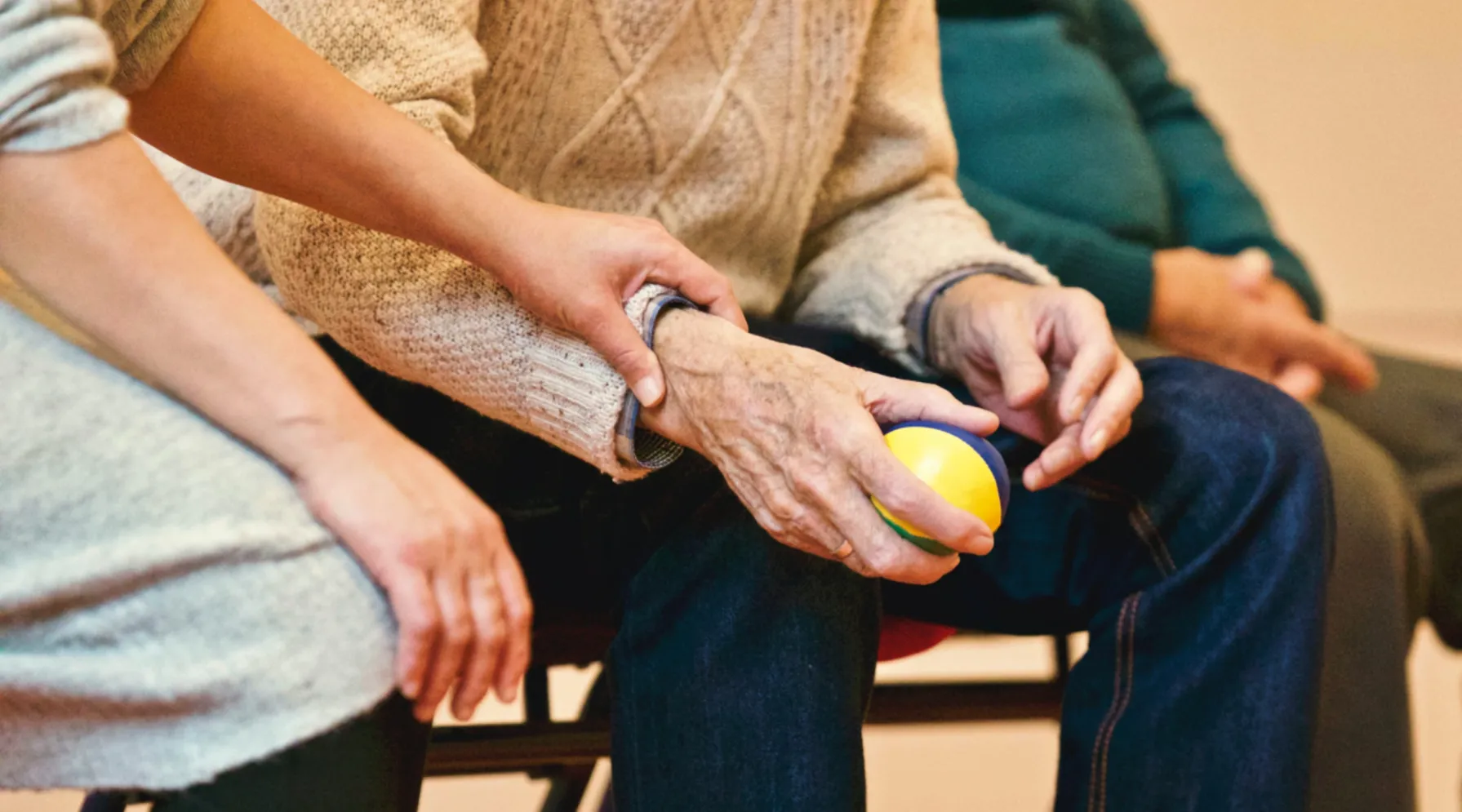 Care worker supporting an elderly person during therapy session, ShiftCare.