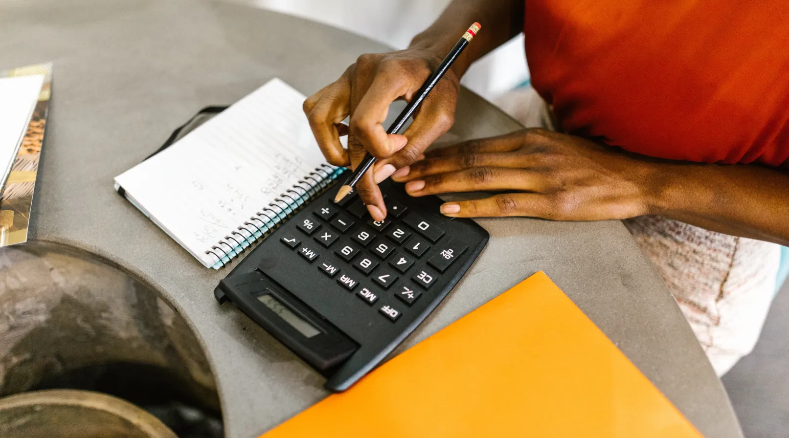 Person using calculator and taking notes while managing finances at desk, ShiftCare.
