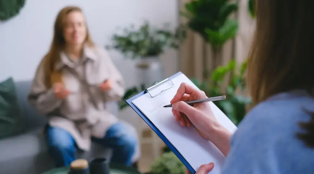Support worker taking client notes during a counseling session using ShiftCare software.